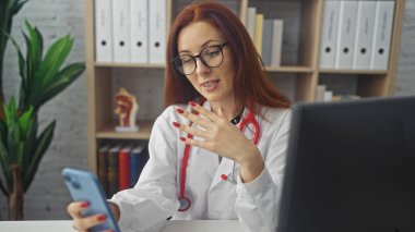 Sağlık uzmanı gibi giyinmiş kızıl saçlı güzel bir yetişkin kadın bir klinikten teletıp seansı düzenliyor..