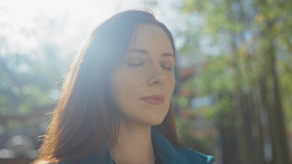 A serene young woman enjoying a peaceful moment in a sunny urban park, embracing nature's tranquility amidst city life.