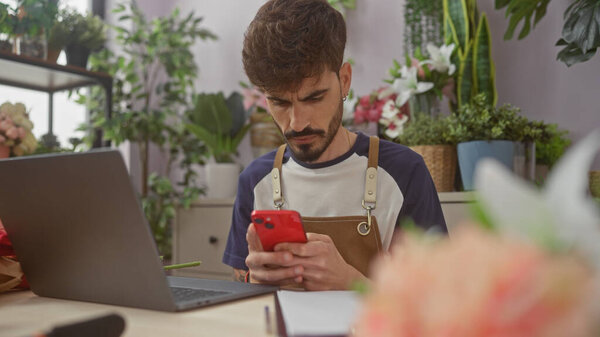 Focused Hispanic Man Uses Smartphone Flower Shop Surrounded Plants Blooms Royalty Free Stock Photos