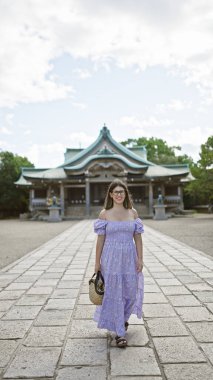 Gözlüklü neşeli Latin güzeli, esmer bir kadın, Osaka 'nın ünlü şatosuna özgüvenli ve kaygısız bir gülümsemeyle poz veriyor, Japonya' nın mirası turizminde neşe ve mutlulukla dolup taşıyor.