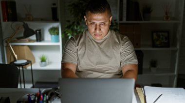 Yakışıklı genç Latin iş adamı, yönetici patron ofiste fazla mesai yapıyor, laptopu üzerinde derin düşüncelere dalmış, başarı için iş stratejileri düşünüyor..