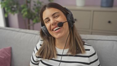 Kulaklıklı, gülümseyen bir kadın kanepede uzanıyor.