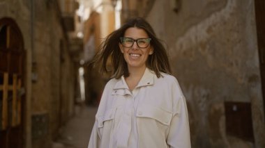 Beyaz ceketli genç İspanyol kadın. Bari 'nin eski kasabasının dar sokaklarında gülümsüyor. Puglia, İtalya..