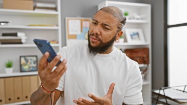 Modern ofis ortamında akıllı telefon kullanan yakışıklı sakallı adam.