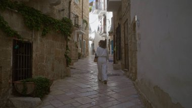 Genç bir İspanyol kadın polignano 'nun pitoresk kaldırım taşlı caddelerinde yürüyor Puglia, İtalya' da bir kısrak, Avrupa 'nın tarihi şehrinin kırsal cazibesine ve güzel mimarisine hayran..