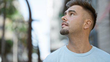 Sakallı, düşünceli, genç bir İspanyol, şehir caddesinde dikilirken dik dik dik bakıyor..