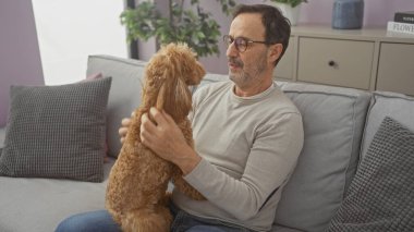 İspanyol bir adam sıcak bir oturma odasında kanişiyle bağ kuruyor.