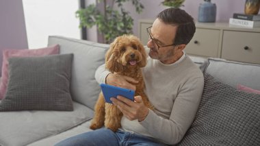 İspanyol adam sıcak oturma odasında tablet kullanırken kanişlerle vakit geçirmeyi seviyor.