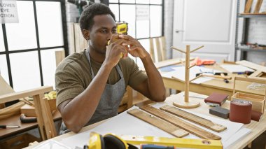 İyi organize edilmiş bir marangozluk atölyesinde, düşünceli bir Afrikalı Amerikalı kahve içiyor..