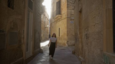 Güzel, genç, İspanyol bir kadın Lecce, Puglia, İtalya 'da dar bir sokakta yürüyor güneşli günün tadını çıkarıyor..