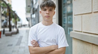 Genç sarışın genç bir çocuk kollarını kavuşturmuş kalabalık bir şehir sokağında, kendine güveni tam bir hava veriyor..