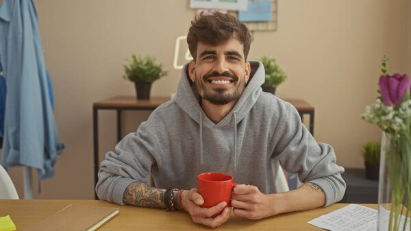 Cheerful Young Hispanic Man Beard Tattoos Holds Red Mug Sitting Royalty Free Stock Images