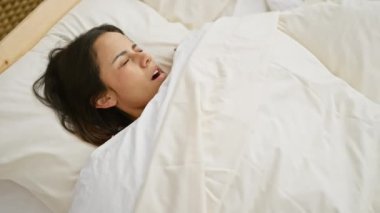 Genç bir İspanyol kadın uyanıyor, yatak odasında gözlerini ovalıyor, sabah tazeliği yayıyor.