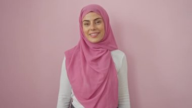 Işıl ışıl genç İspanyol kadın, kendine güveni tam, tesettürlü, doğal mutluluk neşeli gülümsemeyi yansıtıyor. Pembe duvarın üzerinde, başarısını kutlayan gururlu bir portre.