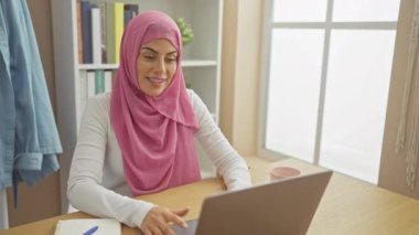 Evde, tesettürlü neşeli, genç bir İspanyol kadın, bilgisayardaki 