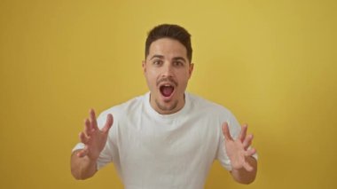 Beyaz t-shirt giyen genç İspanyol adam korkmuş ve ağzı açık bir şekilde şaşırmış bir şekilde duruyor.