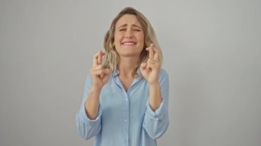 Beyaz bir arka planda yalnız duran neşeli, genç sarışın kadın umut dolu gözlerle kapalı, parmaklar çapraz. Oyuncu, batıl inançlı şans ve inanç jesti.