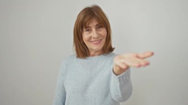 Dost canlısı, orta yaşlı kadın kazak giyiyor, avuç içi yardım teklif ediyor, izole beyaz arka planda neşeli bir gülümsemeyle kabul ediyor ve yardım ediyor..