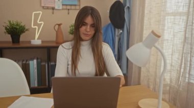 Genç bir İspanyol kadın rahat bir oturma odasında dizüstü bilgisayarını kullandıktan sonra rahatlama ve ev konseptinden esneme hareketleri sergiliyor..