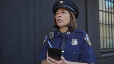 Olgun İspanyol polis üniformalı kadın şehir ortamında not defteri kullanıyor.