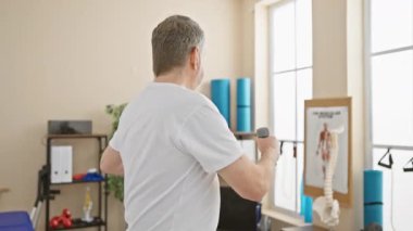 Son sınıf öğrencisi, fizyoterapi kliniğinde dambıllarla egzersiz yapıyor. Sağlık hizmetleri, rehabilitasyon ve sağlık hizmetleri sunuyor..