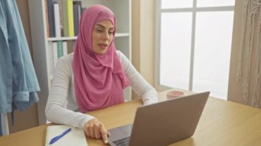 Sinirli, tesettürlü genç İspanyol kadın, bilgisayarında olumsuz bir olaya karşı hoşnutsuzluk ve ret işareti yapıyor..