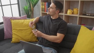 Sakallı, gözlüklü İspanyol bir adam gri koltukta oturmuş dalgın dalgın bakıyor..