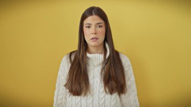 Endişeli yüz ifadesi, sarı arka plandaki işaret parmağıyla gergin bir şekilde kenara çekilen, süveter giyen güzel, genç İspanyol kadının üzerine sinsice süzülür.