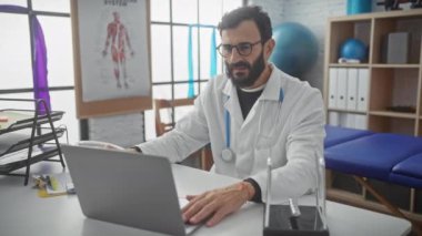 Beyaz önlüklü, yorgun, sakallı bir erkek doktor klinikteki bir bilgisayarı kapatıyor ve uzun bir iş gününün sona erdiğini söylüyor..