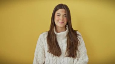 Yüksek sesle gülen, genç, güzel, süveter giyen, ağzı utanç verici dedikodu skandalıyla kaplı, sarı arka planda tek başına duran İspanyol kadın.