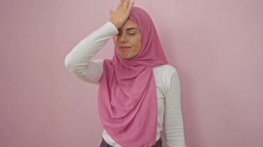 Tüh! Tecrit edilmiş pembe arka planda tesettürlü genç, çekici İspanyol kadın unutkan bir hata yaptığı için pişmanlık duyuyor. Hafızada bir karışıklık, portrede yakalanan bir hata.!