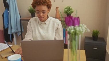 Stresli Afro-Amerikalı kadın evde, krizden endişeli, masaya oturmuş gözlük takıyor, aklı başında, yorgun ve depresif.