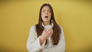 Sıkıntı her şeyi ele geçiriyor, genç, güzel İspanyol kadın yorgun bir şekilde esniyor, uykusuzluk yüzünden okunuyor. Sarı bir kazağın içinde, yorulmuş esnemelerin arasında ağzımı kapatıyorum. izole arkaplan.