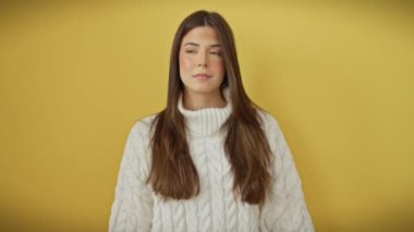 Tüh! Süveter giymiş genç, güzel bir İspanyol kadın, bir eli başının üstünde hatayı fark ediyor, izole edilmiş sarı arka planda umutsuzca dikiliyor.