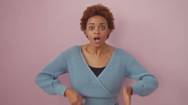 Şok olmuş Afro-Amerikalı bir kadın. Ağzını hatanın üstüne elleriyle kapatıyor. Gizli saklı. Süveter giymiş çekici bir kadının portresi, pembe arka planda sersemlemiş bir sessizlikte duruyor..