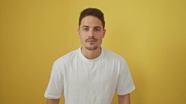 Beyaz tişörtlü, heyecandan bağıran kendinden geçmiş genç İspanyol adam. Kollarını kaldırıp başarısını kutlayan muzaffer bir adam. Parlak sarı arkaplana karşı izole.