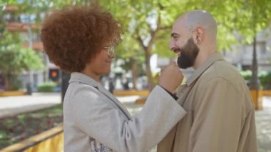 Güneşli bir şehir parkında sevgi dolu bir anı kucaklayan ve paylaşan ırklar arası bir çift..