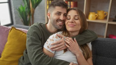 Sevecen erkek ve kadın, sıcak, modern bir oturma odasında kucaklaşıyorlar. Aşkı ve kapalı alanda mutlu bir ilişkiyi tasvir ediyorlar..