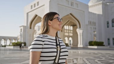 Güneş gözlüklü genç bir kadın Abu Dabi 'deki Büyük Qasr al Watan Sarayı' nı geziyor..
