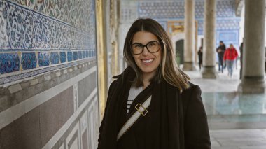 İstanbul 'daki tarihi topkapı sarayında, süslü fayanslar ve mermer sütunlarla çevrili gülümseyen kadın..