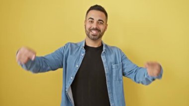 Neşeli İspanyol adam sarı arka planda duruyor, kot gömlek giyiyor, sağlıklı dişlerini sırıtarak gösteriyor! Diş sağlığı yerinde!