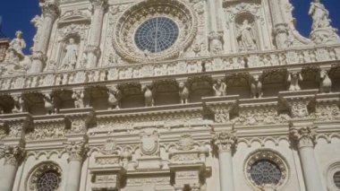 Karmaşık oymalarla süslü bir katedral cephesi ve açık mavi gökyüzüne karşı İtalyan barok mimarisini temsil eden ders, puglia şeklinde büyük bir gül penceresi..