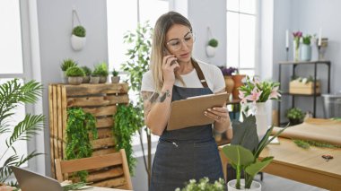 Çiçekçi, çiçekçi, çiçekçi dükkanında dosya ve telefon ile birden fazla iş yapan bir kadın..