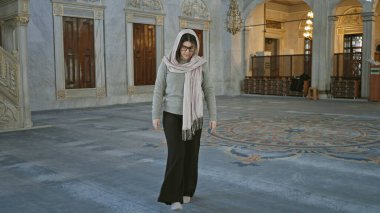 Genç kadın tesettürlü güzel İstanbul camiinin içinde karmaşık bir İslami mimari ile yürüyor..