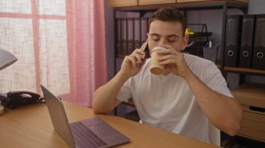 Ofiste telefonla konuşurken kahve içen sakallı, genç bir İspanyol..
