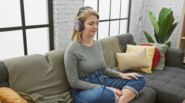 Kafkasyalı rahat yetişkin bir kadın kulaklıklarla müzik dinliyor.