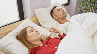 Bir çift, rahat bir yatak odası ortamında huzur içinde uyur. Huzurlu bir ilişki mahremiyeti anı yakalar..