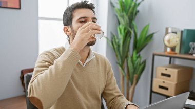 Modern bir ofiste kahve içen yakışıklı bir İspanyol iş yerinde genç bir profesyoneli temsil ediyor..