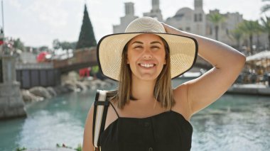 Güneş şapkalı, gülümseyen bir kadın Dubai 'deki su yolları boyunca Madinat Jumeirah' ı geziyor..