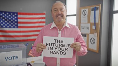 Olgun bir adam, bir Amerikan bayrağıyla bir Amerikan oy merkezinin içinde bir tabela tutuyor..
